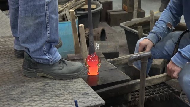 Glassblower also known as gaffer blowing glass working red hot vase putting it in wooden mall cooling it down again always turning crystal to keep it round and smooth located at glassmith workshop 4k