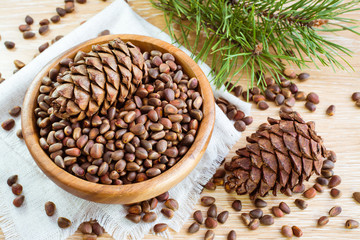 Спелые кедровые шишки, кедровые орехи и ветки сосны на столе © elenarui