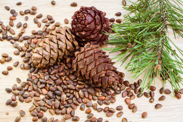 Спелые кедровые шишки, кедровые орехи и ветки сосны на деревянном столе © elenarui