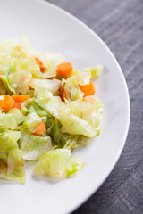 Steamed carrots and cabbage on dark wood background