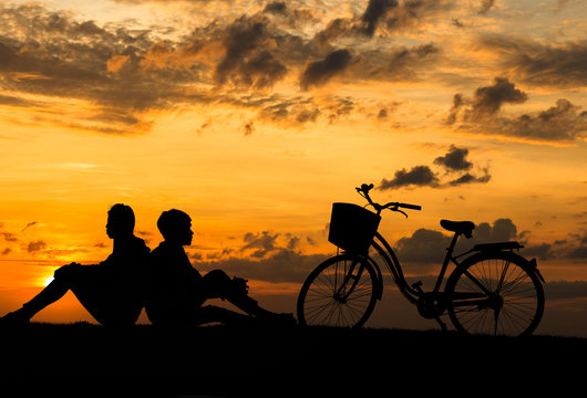 Silhouette of sweet couple in love happy time and bicycle in bea
