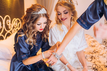 bride with bridesmaids in hotel room in the morning wearing ib robe and emracing each other. robe.