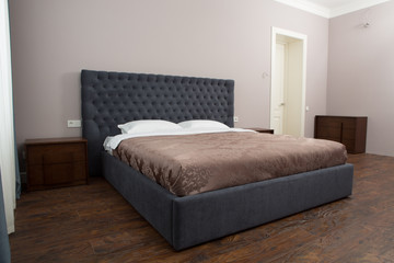 View of double bed in bedroom with two white pillows on. Representation of bed in hotel or luxurious house.