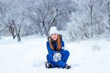 Fototapeta premium Happy laughing baby in winter forest. Young girl playing in the snow-covered snow park