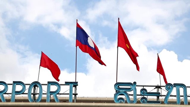 Laos national flag and a red flag with the hammer and sickle flutters over the airport. 