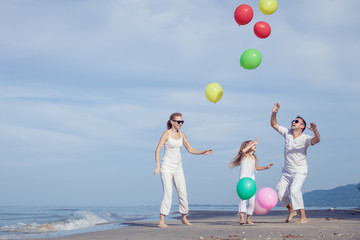 Happy family playing with balloons on the beach at the day time.