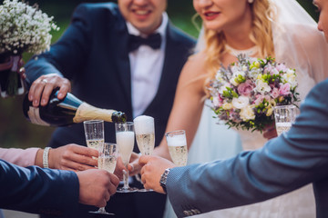 Bride and groom with happy groomsmen and bridesmaids having fun and popping champagne, luxury wedding celebration, hilarious moment. Newlyweds fun with friends.