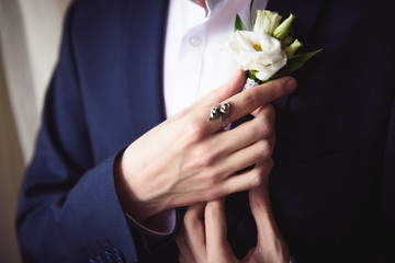 groom boutonniere adjusts his hand in a jacket pocket