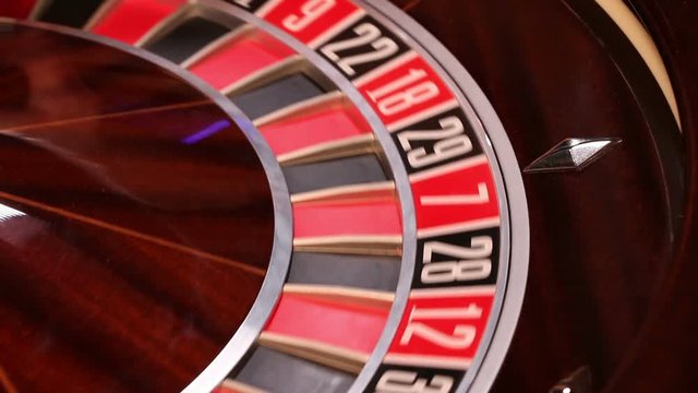 Casino roulette in motion, the spinning wheel ball and croupier hand