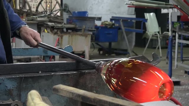 Glassblower also known as gaffer blowing glass working orange hot vase sanding it with wet sandpaper cooling it down always turning crystal to keep it round and smooth located at glass workshop 4k