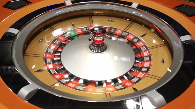 Roulette table in casino. Ball in the rotating gambling machine. Wooden roulette wheel.