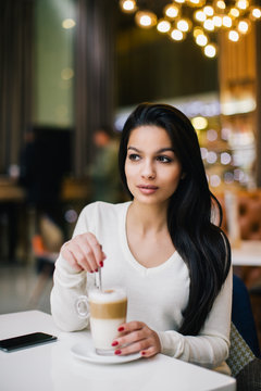 Young woman at cafe drinking coffee