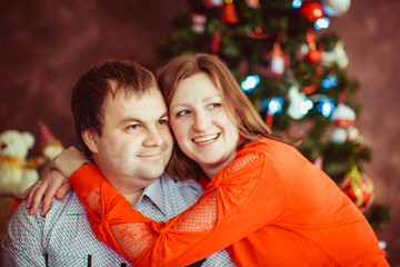 The lovely couple in love sitting near Christmas Tree