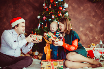 The mother,father and son keeps presents  near Christmas tree