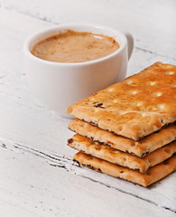 Cup of coffee and delicious baked cookies on old wooden background.