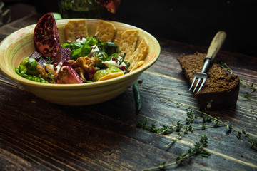 Fresh salad with chicken, tomatoes, crisps, mushrooms, cheese, fruits (arugula, mesclun, mache) on wooden background close up. Healthy food.