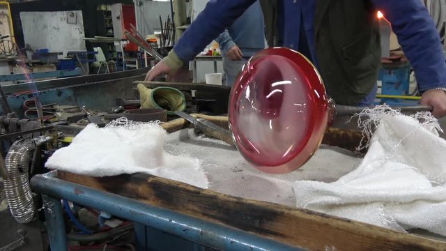 Glassblower also known as gaffer cutting loose the final vase product freshly made out of oven by glass worker amazing manual labor work of art located at glassmith crystal workshop or factory 4k