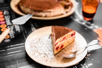 Piece of cake with cherries on a dark table