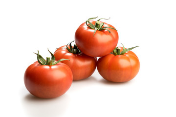 Four realistic looking tomatoes lying piled up isolated in a whi