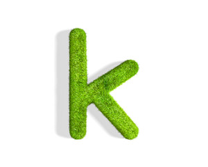 Grass letter K in lowercase format from top angle with shadow on ground.