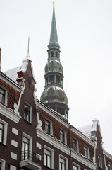 Spire of St Peter's cathedral behind old building facade in Riga, Latvia