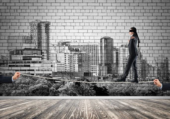 Business concept of risk support and assistance with man balancing on rope