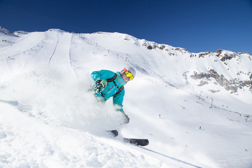 Skier skiing downhill in high mountains