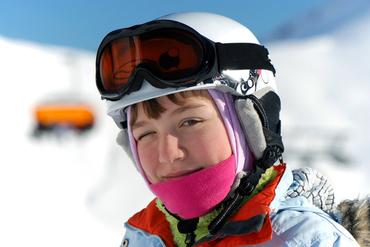 beautiful active smiling happy small young caucasian girl in helmet and ski jacket with ski googles during winter outdoor leisure recreat