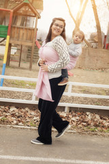 Young mother with her baby boy in a baby carrier scarf