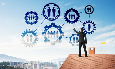 Businessman on house roof presenting teamwork and connection concept. Mixed media