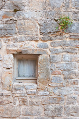 Fototapeta na wymiar Small window at stone wall in Old Town of Budva, Montenegro.