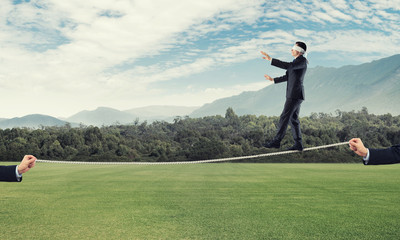 Business concept of risk support and assistance with man balancing on rope