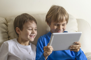 Fototapeta na wymiar Children with tablet PC. Boys looking at screen, smiling and playing games or watching video. People education learning technology leisure concept