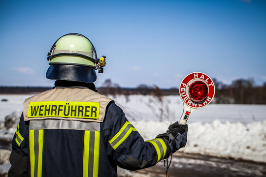HDR - Feuerwehrmann im Einsatz sperrt mit einer Haltkelle die Stra&szlig;e