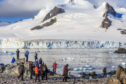 Group of tourists looking at the glacier at the stony shore of H