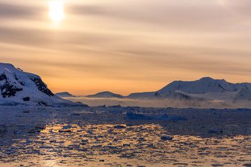 Sunset over the mountains and icebergs at Lemaire Strait, Antarc