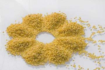 raw millet poured in form of flower on white background