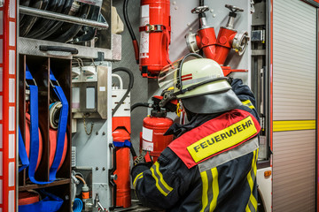 HDR - Feuerwehrmann belädt das Löschfahrzeug mit einem Feuerlöscher