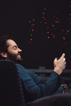 Happy Young Man Relaxing On Sofa And Using Cellphone