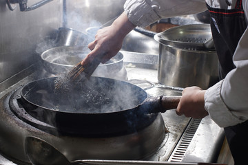 Cleaning wok with wooden sticks and metal wire
