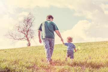 Naklejka na ściany i meble Father and son walking in a field