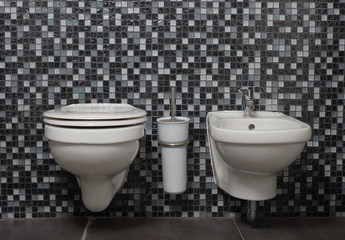 Bathroom toilet in modern minimalistic design with black mosaic tiles wall.