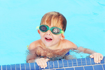 Naklejka premium Smiling preschool boy wearing googles in pool