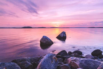 Fotobehang Lichtroze Violet toning kustlandschap met grote stenen op de voorgrond. Locatie: Zweden, Europa.