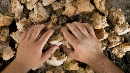 CLOSE UP: Bread in hands on black background