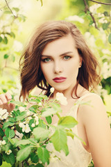 Naklejka premium Cute Girl in Spring Park. Fashion Model Woman on Flowers