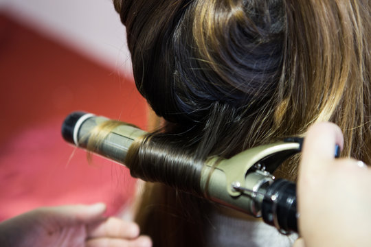 Parrucchiera lavora sui capelli con la piastra calda 
