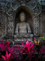 Balinese Hindu Temple Statue With Colourful Bright Pink Flowers In Foreground - Bali, Indonesia