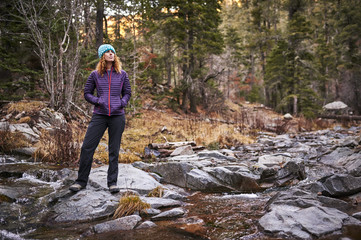a young woman hiking next to a mountain river