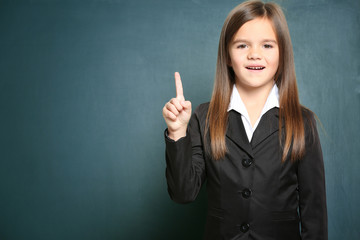 Cute little girl standing on green blackboard background